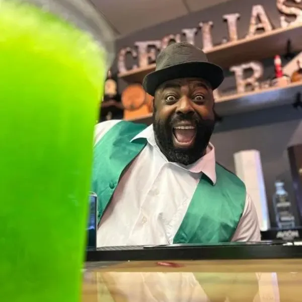 a man smiling from behind a bar